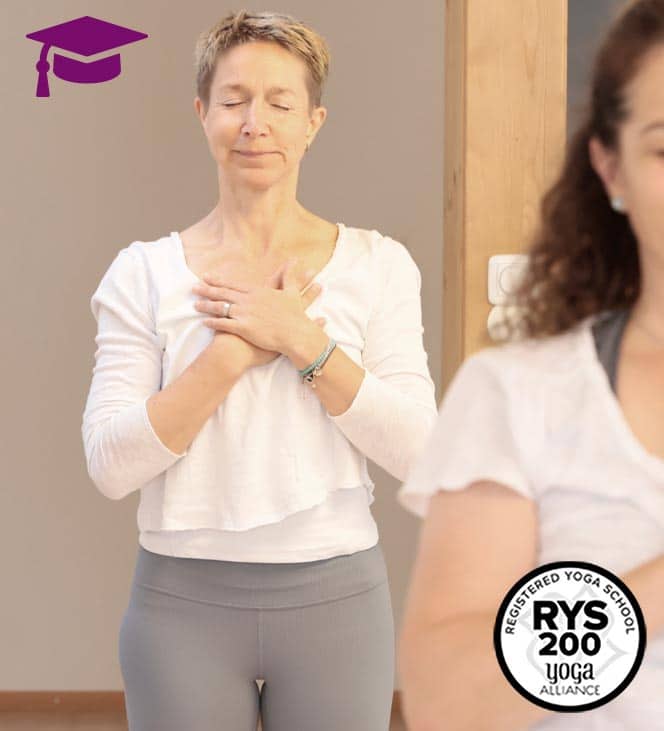 Teilnehmerinnen einer Yogalehrerausbildung von Yogaplus Studio Mainz bei einer meditativen Achtsamkeitsübung mit geschlossenen Augen und gefalteten Händen im Ausbildungsraum. – Das Bild enthält ein Symbol für eine zertifizierte Yogalehrerausbildung.