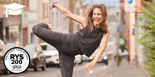 Yogalehrerin Nicole Schmid versucht im dunkelgrauen Yogaoutfit mitten auf der Gaustraße zwischen den Straßenbahngleisen die Asana 'NATARAJASANA' zu demonstrieren und lacht in die Kamera
