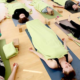 Yogaplus Yogalehrerschüler während der Entspannungsübung liegen zugedeckt auf ihren Yogamatten