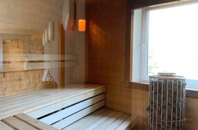 Blick in die Saune mit großem Panoramafenster und rundem mit Lavasteinen gefüllten Saunaofen (Foto: Copyright by © Hotel Miramonte/Bad Gastein)