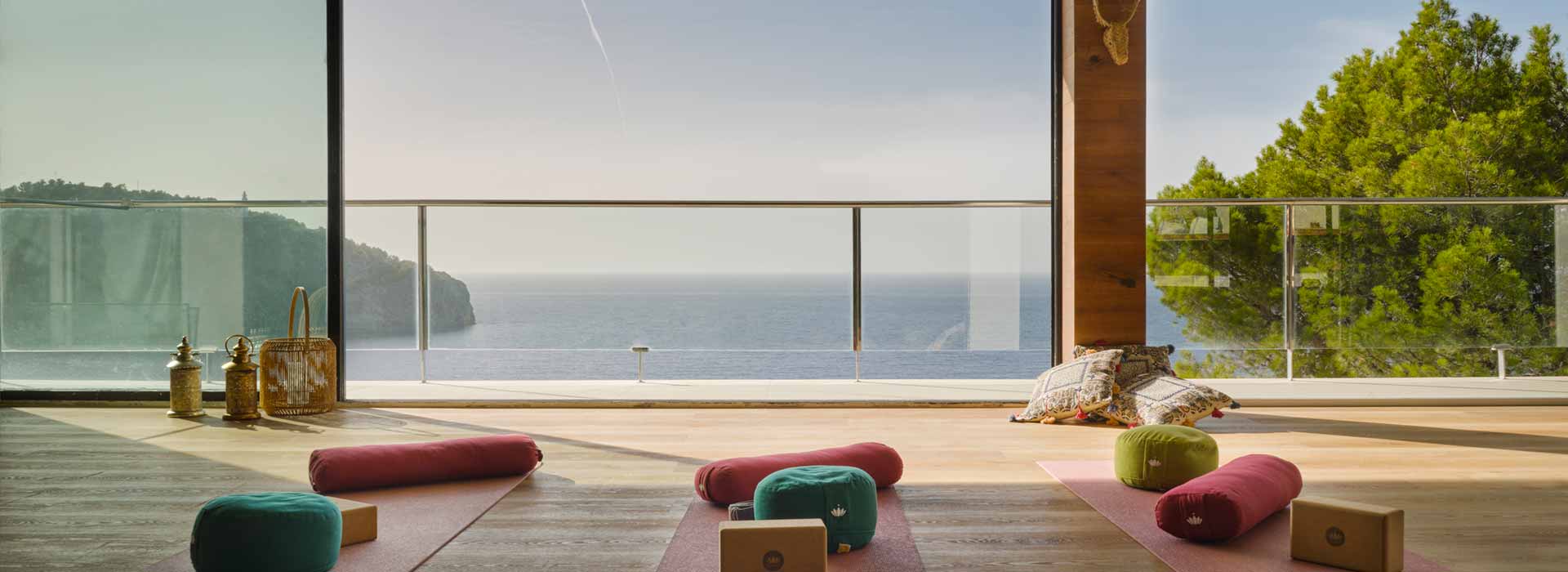 Blick aus dem mit Holzdielen ausgelegten Yoga Soul Room durch seine großen bodentiefen Panoramafenster auf das Meer