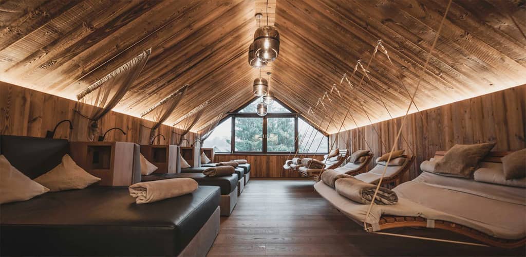 Der stilvoller Ruheraum des Poolhauses vom Pfalzblick Wald Spa Resort mit Holzwänden und -decke, gemütlichen Liegen und stimmungsvoller Beleuchtung lädt zum Entspannen ein.