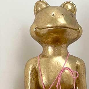 In einer Raumecke sitzt als stilisierte Plastik ein goldener Frosch im Lotussitz mit auf seinen Knien algelegten und nach oben gerichteten Händen und meditiert (Foto: © Yogaplus/Susanne Weisheit)