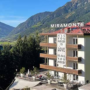 Blick in das Gasteinertal bei strahlend blauem Spätsommerhimmel mit dem Hotelbau MIRAMONTE im Vorder- und der Bergkette der Hohen Tauern in Hintergrund. (Foto: © Yogaplus/Susanne Weisheit)