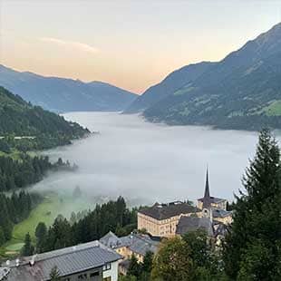 Blick vom Balkon des Hotelzimmers mit Morgennebel über dem Gasteinertal und gelblichem Sonnenaufgangsschimmer am klaren Morgenhimmel (Foto: © Yogaplus/Susanne Weisheit)