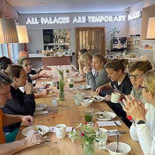 Die Teilnehmer des Yogaplusretreats sitzen morgends beim reichhaltigen Frühstück im Fpühstückssaal des Hotels Miramonte zusammen an einem riesigen hellen Holztisch. (Foto: © Yogaplus/Susanne Weisheit)