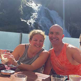 Drei Teilnehmer:innen des Yogaplusretreats sitzen in einem Ausflugslokal vor dem Bad Gasteiner Wasserfällen bei Latte Macchiato und Cappuchino und posen in die Kamera. (Foto: © Yogaplus/Susanne Weisheit)