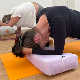 Die Teilnehmer:innen des Yogaplustrtreats praktizieren Yin-Yogaübungen auf ihren Matten mit Bolstern und Stützblöcken. (Foto: © Yogaplus/Susanne Weisheit)