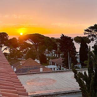 Sonnenaufgang über dem 'Hostal de La Gavina' mit roten Ziegeldächern, Bäumen und Blick aufs Meer. (Foto: © Yogaplus/Susanne Weisheit)